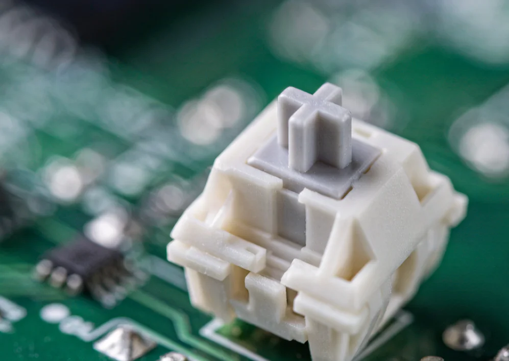 Extreme macro close-up of a mechanical keyboard switch stem and spring, the component most often responsible for chattering