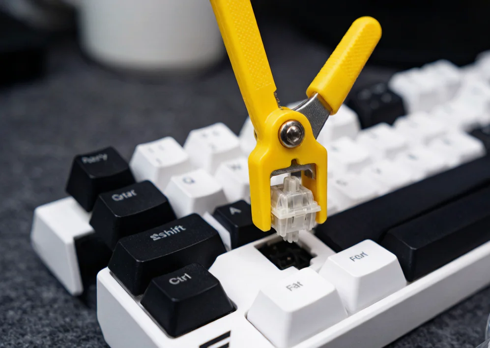 A yellow switch puller tool removing a mechanical key switch from its hot-swap socket for cleaning or replacement